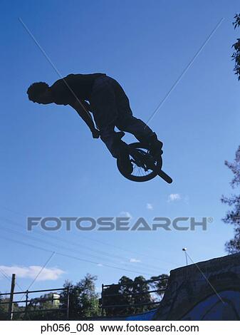 Stock Photo - Male BMX stunt rider in mid-jump . Fotosearch