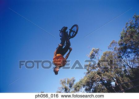 Stock Photograph - Male BMX stunt rider in mid-jump . Fotosearch