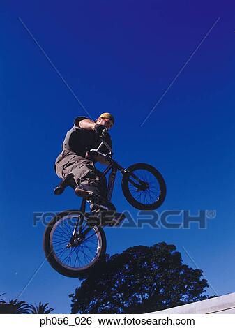 Stock Photograph - Male BMX stunt rider in mid-jump . Fotosearch