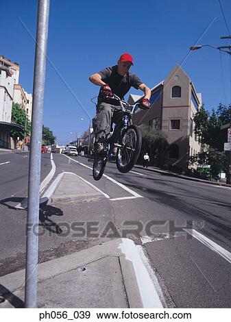 Young man in mid-air jump on bike, city scene View Large Photo Image Stock Photo - Young man in mid-air jump on bike, city scene. Fotosearch