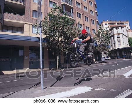 Young man in mid-air jump on bike, city scene View Large Photo Image Stock Photograph - Young man in mid-air jump on bike, city scene. Fotosearch