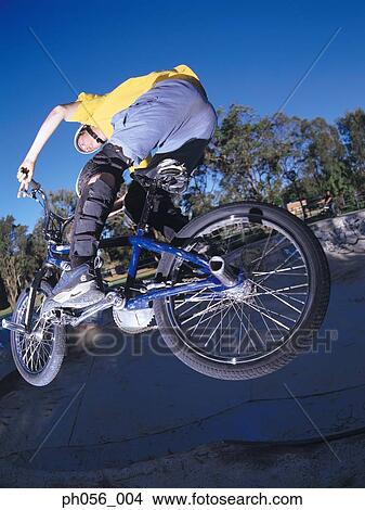 Young man performing bike stunt on ramp View Large Photo Image Picture - Young man performing bike stunt on ramp. Fotosearch