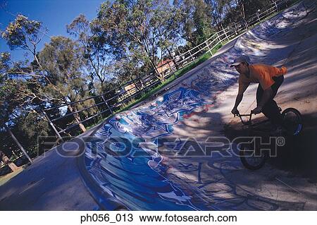 Young man performing bike stunt on ramp View Large Photo Image Stock Image - Young man performing bike stunt on ramp. Fotosearch