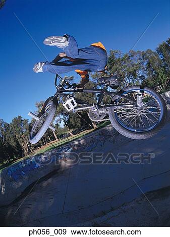 Young man performing bike stunt on ramp View Large Photo Image Stock Photo - Young man performing bike stunt on ramp. Fotosearch