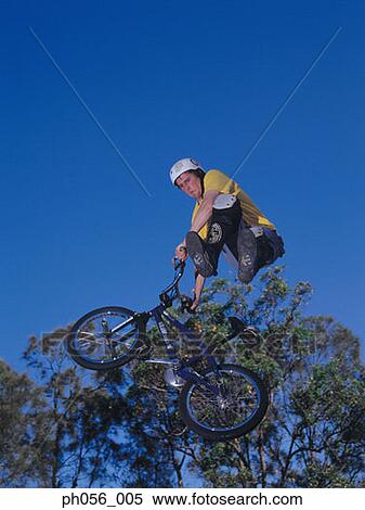 Young man performing bike stunt on ramp View Large Photo Image Stock Photography - Young man performing bike stunt on ramp. Fotosearch