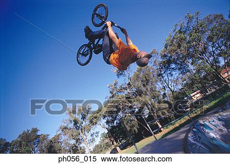 Stock Photography - Young man performing bike stunt on ramp. Fotosearch