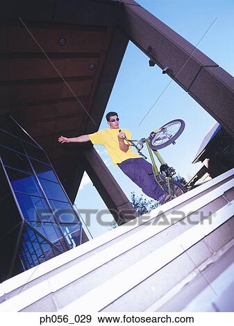 Stock Photo - Young man performing bike stunt. Fotosearch