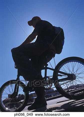Young man resting on BMX on pavement, silhouette View Large Photo Image Stock Photo - Young man resting on BMX on pavement, silhouette. Fotosearch