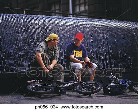 Young men resting on BMX on water fountain View Large Photo Image Picture - Young men resting on BMX on water fountain. Fotosearch