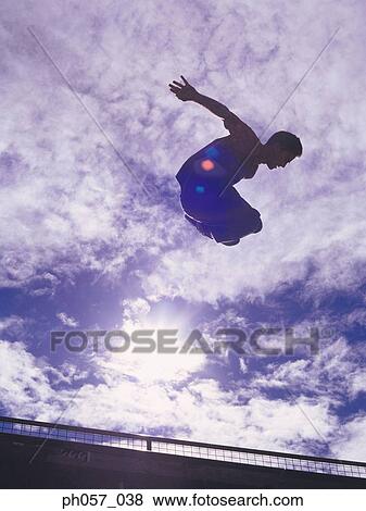 Stock Photo - In-line skater performing stunt in mid-air . Fotosearch