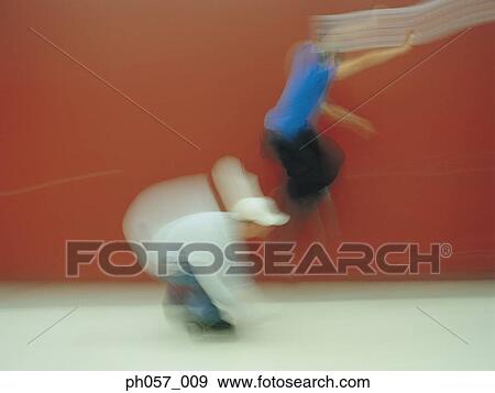 Stock Photo - In-line skaters performing stunt in skating ring (blurred motion) . Fotosearch