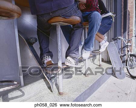 Stock Photograph - Friends at sidewalk café, skateboards and bicycle, lower section. Fotosearch