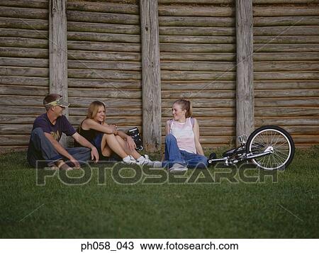 Teenagers sitting together on grass talking View Large Photo Image Stock Image - Teenagers sitting together on grass talking . Fotosearch