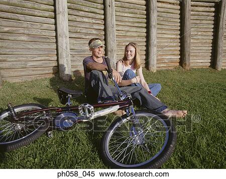 Stock Photography - Young couple sitting together on grass talking . Fotosearch