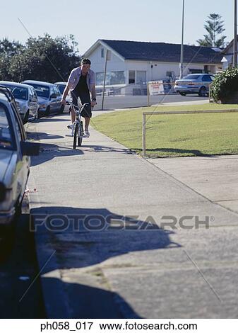Young man cycling on pavement View Large Photo Image Stock Photo - Young man cycling on pavement. Fotosearch
