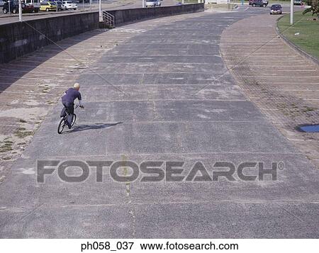 Stock Photo - Young man cycling on pavement. Fotosearch