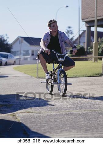 Stock Photograph - Young man cycling on pavement. Fotosearch