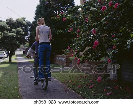 Young man cycling with young woman on back of bike, rear view View Large Photo Image Stock Photo - Young man cycling with young woman on back of bike, rear view . Fotosearch