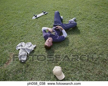 Stock Photo - Young man lying on grass . Fotosearch