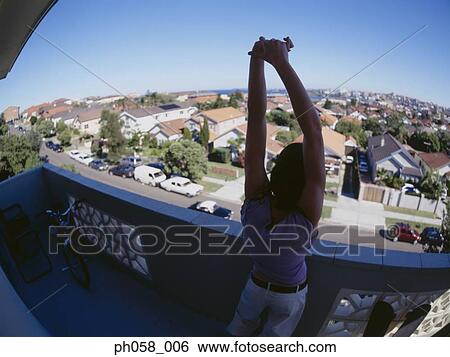 Young man stretching his arms at balcony View Large Photo Image Stock Photograph - Young man stretching his arms at balcony. Fotosearch