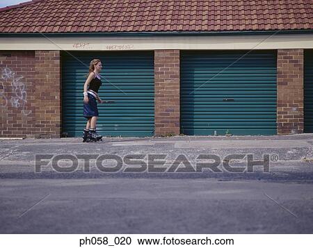 Stock Image - Young woman skating on pavement. Fotosearch