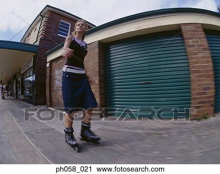 Stock Image - Young woman skating on pavement. Fotosearch