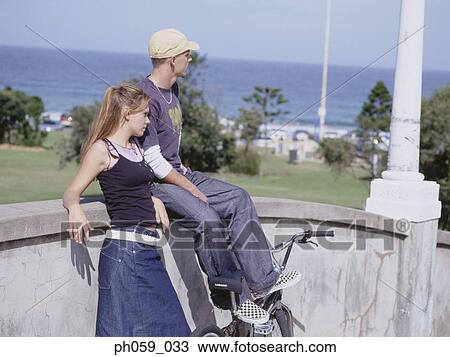 Couple sitting on low wall looking away View Large Photo Image Stock Image - Couple sitting on low wall looking away. Fotosearch