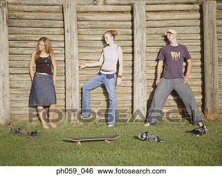Stock Photograph - Three young people posing in front of wooden fence. Fotosearch