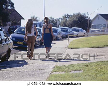 Two women walking on walkway holding skateboards, rear view View Large Photo Image Stock Image - Two women walking on walkway holding skateboards, rear view . Fotosearch