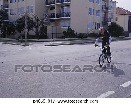Young man cycling on street View Large Photo Image Stock Photo - Young man cycling on street. Fotosearch