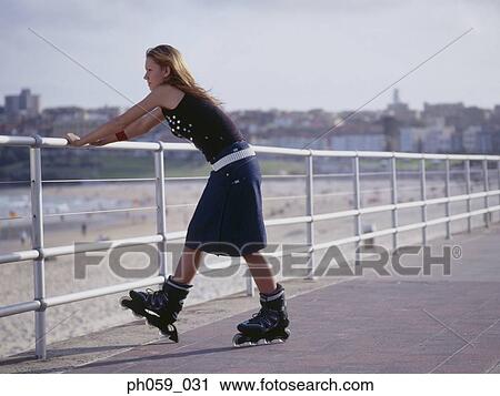 Stock Image - Young woman in inline skate leaning on railing . Fotosearch