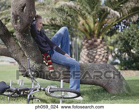 Young woman lying on bent tree trunk View Large Photo Image Picture - Young woman lying on bent tree trunk . Fotosearch