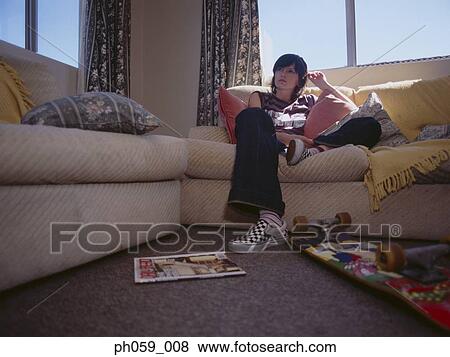 Young woman sitting on sofa View Large Photo Image Stock Photo - Young woman sitting on sofa. Fotosearch