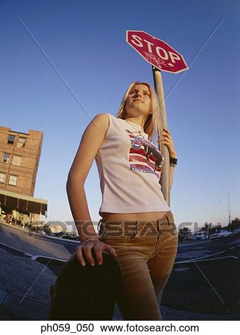 Young woman standing near stop sign, looking away View Large Photo Image Stock Image - Young woman standing near stop sign, looking away. Fotosearch