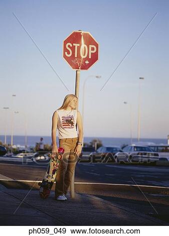 Young woman standing near stop sign, looking away View Large Photo Image Stock Photo - Young woman standing near stop sign, looking away. Fotosearch