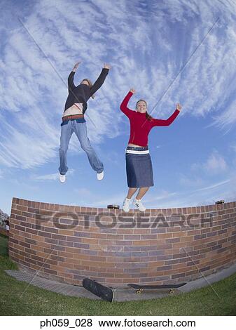 Young women jumping from wall, arms outstretched View Large Photo Image Stock Photo - Young women jumping from wall, arms outstretched . Fotosearch