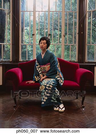 Stock Photo - Japanese woman in kimono sitting on sofa. Fotosearch
