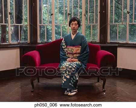 Stock Photograph - Japanese woman in kimono sitting on sofa. Fotosearch
