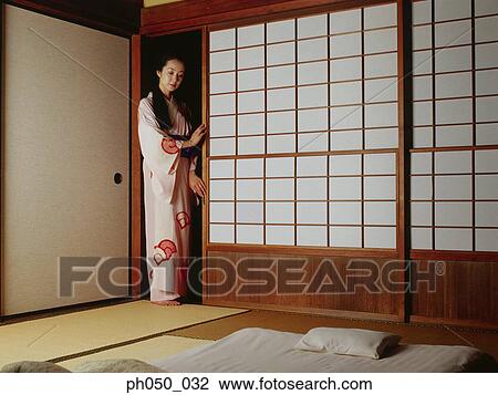Stock Image - Japanese woman in kimono, standing by the door. Fotosearch