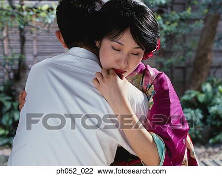 Stock Image - Japanese couple embracing in garden. Fotosearch