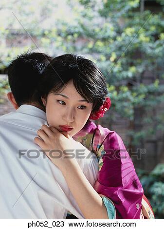 Stock Image - Japanese couple embracing in garden. Fotosearch