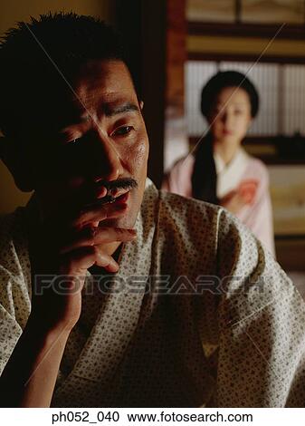 Stock Image - Japanese woman and man (focus on Japanese man smoking cigarette). Fotosearch