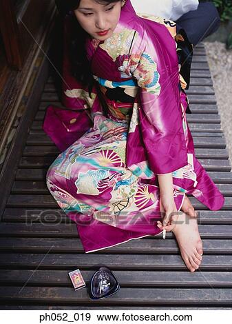 Stock Photo - Traditional Japanese couple smoking in backyard garden, portrait. Fotosearch