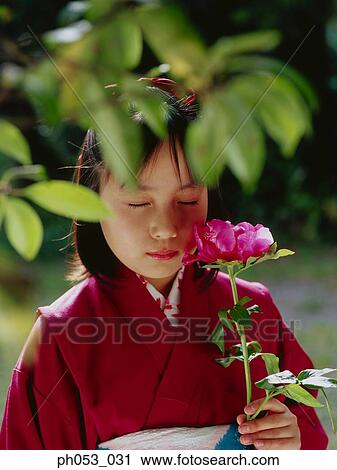 Stock Image - Japanese girl in kimono holding a stalk of flower. Fotosearch