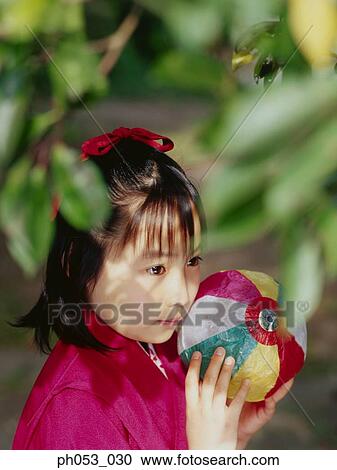Stock Image - Japanese girl in kimono holding paper ball. Fotosearch