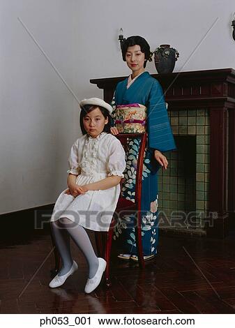Stock Image - Japanese woman in kimono, portrait by girl sitting in chair, portrait . Fotosearch