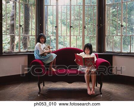 Stock Image - Two girls on a sofa . Fotosearch