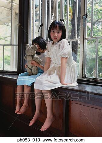 Two girls sitting on window ledge View Large Photo Image Stock Image - Two girls sitting on window ledge . Fotosearch