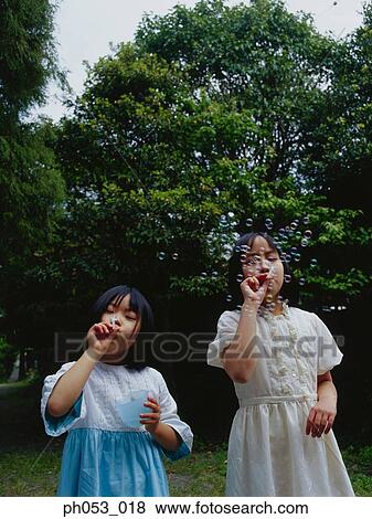 Two young girls blowing bubbles View Large Photo Image Stock Photo - Two young girls blowing bubbles. Fotosearch