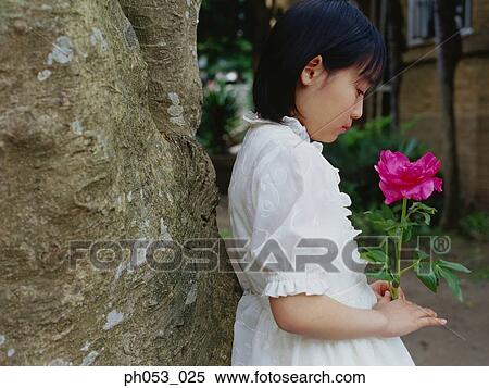 Stock Photography - Young girl holding flower, close-up, portrait. Fotosearch